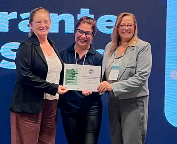 Mascate Restaurante-Escola conquista selo internacional em turismo sustentável Solenidade de entrega da certificação aconteceu durante a 2ª Conferência da Green Destinations Latinoamérica O Mascate Restaurante-Escola, do Senac Pernambuco, conquistou o selo internacional Good Travel Seal – categoria Prata, concedido pela organização holandesa Green Destinations. A certificação foi entregue ontem (18), durante a 2ª Conferência da Green Destinations Latinoamérica, realizada no Hotel Senac Barreira Roxa, em Natal (RN), entre os dias 17 e 19 de junho. O selo reconhece instituições que adotam práticas sustentáveis no setor de turismo e reforça o compromisso do Senac PE com a responsabilidade ambiental, social e cultural. Representando o Senac PE, estiveram presentes a diretora de Projetos Estratégicos, Maria Goretti Gomes; a gerente de Gastronomia e Turismo, Mércia Araújo; a analista de Hospitalidade, Elizabete Sabóia; e a assistente técnica, Ângela Tenório. Outros colaboradores do Departamento Regional de Pernambuco também prestigiaram o evento, junto com representantes do município de Lagoa Grande – que tem a intenção de implementar o Programa DEL – acompanhados pelo gerente do Senac Petrolina, Sebastião Gomes. A conferência reuniu autoridades, gestores e especialistas de oito países para debater estratégias e práticas de turismo sustentável. Entre eles, a conselheira de Desenvolvimento Sustentável da Embaixada da Alemanha, Petra Schmidt; o presidente da Green Destinations Foundation, D'Arcy Dornan; o presidente do Instituto DEL, Alexandro Bastos; a coordenadora de projetos globais da BBW, Anne Oertel; e a coordenadora geral de projetos do Instituto de Desenvolvimento Econômico Local (IDEL), Aline Nandi. Segundo o presidente do Sistema Fecomércio/Sesc/Senac PE, Bernardo Peixoto, “a certificação ratifica nossos esforços em oferecer experiências que valorizam o meio ambiente, a cultura local e o bem-estar coletivo. É um orgulho para todo o Sistema Fecomércio-PE”. Turismo sustentável – O evento também foi marcado pela entrega da certificação internacional Top 100 Stories a três cidades pernambucanas: Fernando de Noronha, Sirinhaém e Tamandaré — municípios assistidos pelo programa DEL Turismo promovido pelo Sistema Fecomércio PE, por meio do Senac PE. As cidades se destacam pelas melhores práticas de gestão sustentável no mundo. Critérios – No Brasil, o programa Good Travel Seal é implementado em parceria com a Rede DEL Turismo, que reúne instituições públicas e privadas que promovem o turismo sustentável em mais de 25 destinos nas cinco regiões do país. A avaliação dos empreendimentos considera critérios ligados a princípios ambientais, sociais, culturais e de gestão. A certificação é dividida em três níveis: bronze (a partir de 50% dos critérios atendidos), prata (a partir de 75%) e ouro (a partir de 95%). Green Destinations – A fundação holandesa apoia destinos e empresas ao redor do mundo a adotarem práticas mais sustentáveis no turismo. O Good Travel Seal é adotado em mais de 90 países e apoia mais de 400 destinos ao redor do mundo, promovendo práticas de turismo responsável alinhadas a padrões globais. A certificação está disponível para negócios de diferentes perfis no setor de turismo, oferecendo instrumentos de avaliação baseados nos critérios do Global Sustainable Tourism Council (GSTC). A diretora de Projetos Estratégicos, Maria Goretti Gomes, avalia que a certificação reforça o compromisso do Senac PE com a expansão do turismo sustentável nos territórios. “Esse evento é de extrema importância, trazendo muitos aprendizados valiosos que poderemos aplicar em nossos municípios que estão em processo de implantação do DEL. A certificação valoriza o papel fundamental do Mascate na formação dos alunos e na contribuição para a sociedade. Já estamos nos passos finais para a assinatura do contrato com o município de Lagoa Grande, avançando com muita expectativa e comprometimento”, ressalta. A gerente de Gastronomia e Turismo, Mércia Araújo, comemorou a conquista e destacou a projeção para os próximos passos. “A certificação é apenas o começo. É o incentivo de um trabalho que queremos levar até alcançar o nível ouro. Nossa intenção é apresentar esse projeto aos empresários do setor, multiplicar as ações e buscar um resultado ainda mais expressivo em Pernambuco”, pontua.